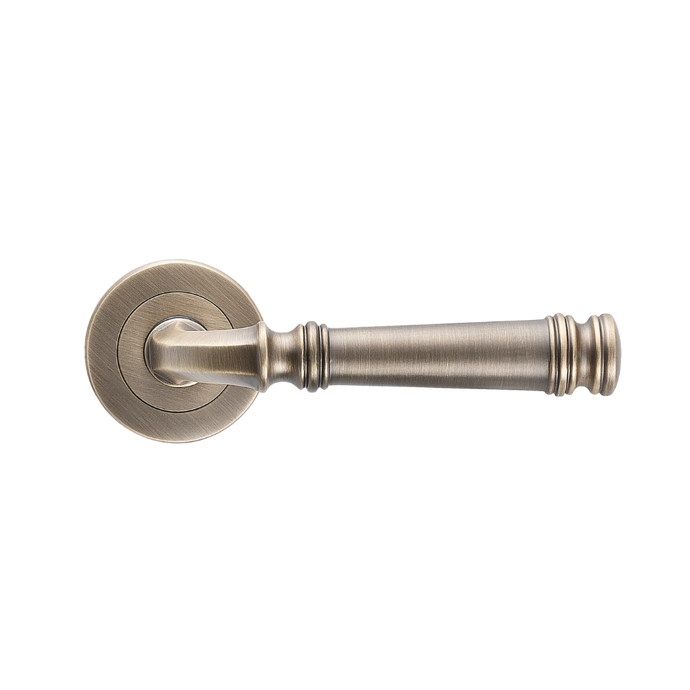 Product picture of the Tuscany Lever on Round Rose in Antique Brass on a white background.